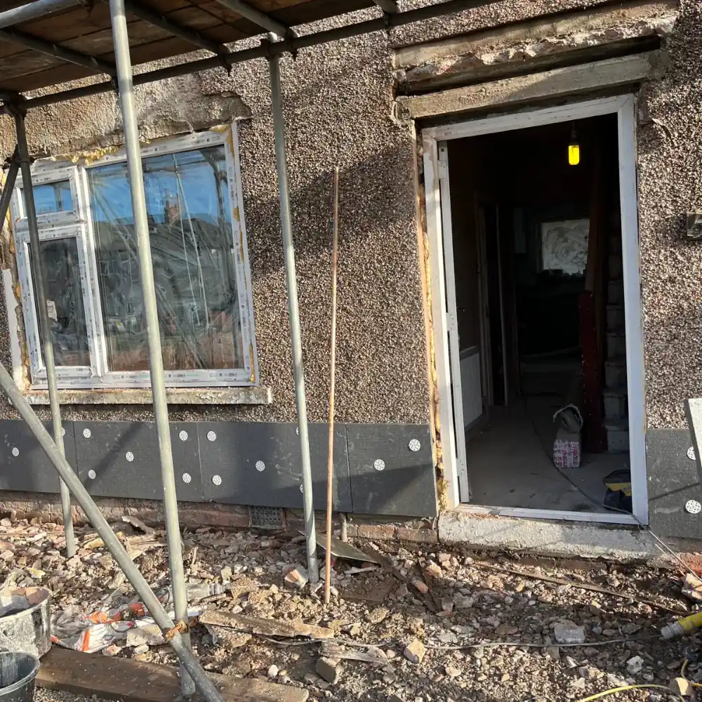 Scaffolding covering a terraced house facade for a traditional sand and cement render upgrade